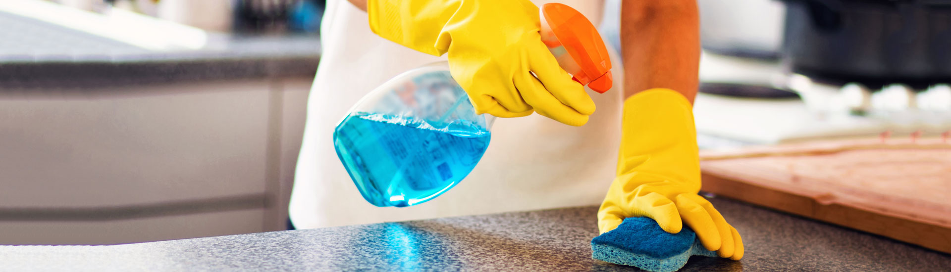 A Cleaner Cleaning the Kitchen With a Blue Cloth and Spray